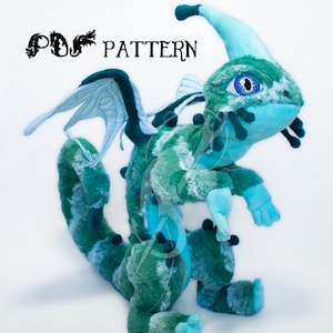 Peut inclure: Un dragon en peluche bleu et turquoise avec une grande gueule ouverte et un seul gros œil. Le dragon a une longue queue fine et une paire d'ailes. Le dragon est debout sur une surface blanche.