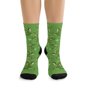 May include: A pair of green socks with a repeating pattern of cartoon green dragons blowing bubbles. The socks are black at the toe and heel.