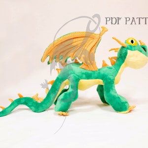 May include: A green and yellow plush dragon with orange wings. The dragon is standing on all fours and has a long tail. The dragon is a popular character from the animated movie How to Train Your Dragon.