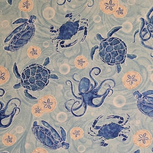 May include: A blue and white fabric with a repeating pattern of sea creatures, including sea turtles, crabs, octopuses, and seashells. The background is a light blue with a wavy pattern.
