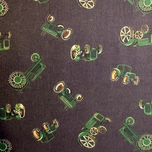 May include: A dark gray fabric with a repeating pattern of green toy tractors. The tractors have black wheels and yellow accents.