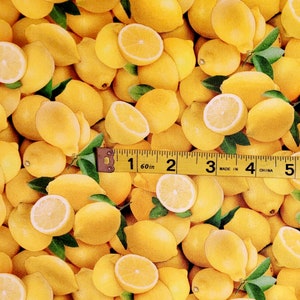 May include: A close-up of a fabric with a yellow lemon print. The fabric is covered in lemons of various sizes and shapes, some cut in half to show the inside.