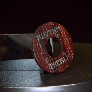 May include: A wooden knob with the words "Rhythm" and "Treble" engraved on it. The knob is brown and has a hole in the centre.