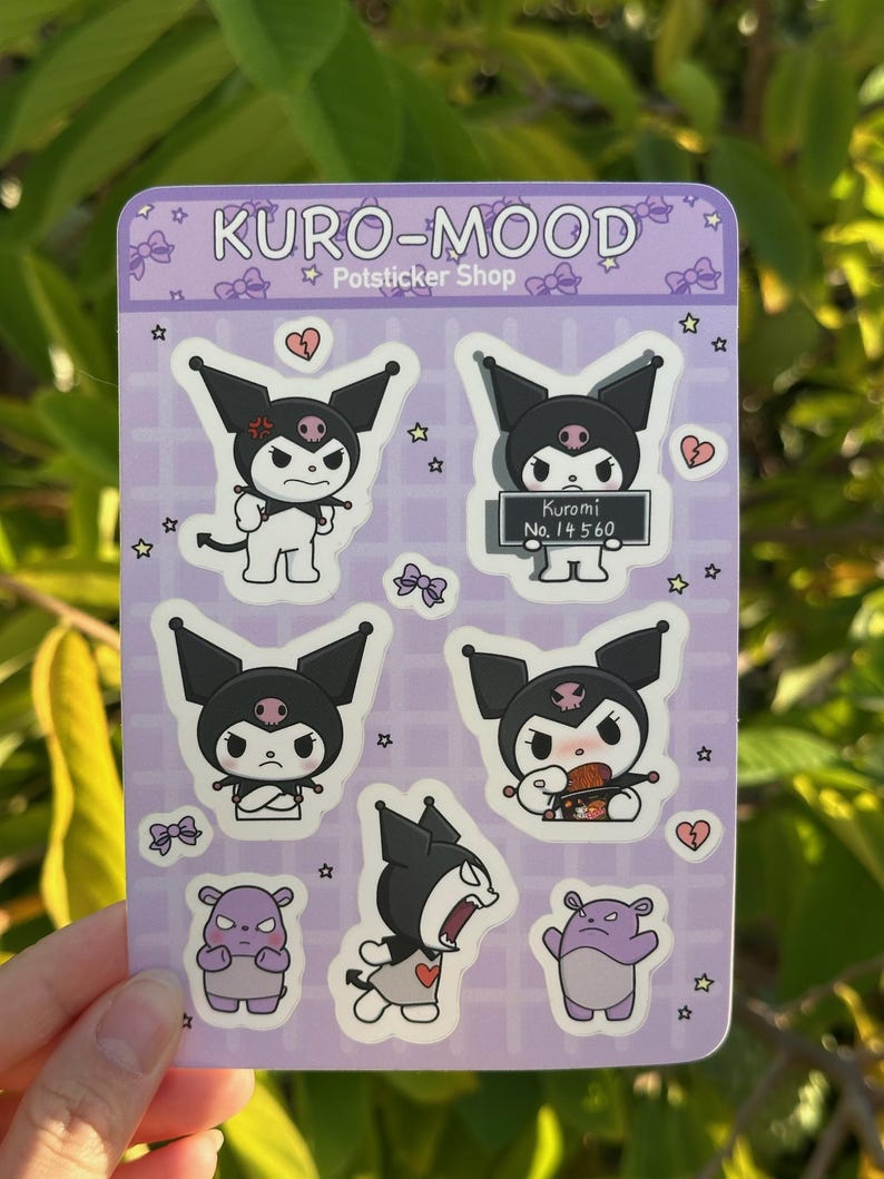 May include: A sheet of stickers featuring Kuromi, a black and white Sanrio character with a skull and crossbones on her head. The stickers are on a purple background with white stars and hearts. The text "KURO-MOOD Potsticker Shop" is at the top of the sheet. One sticker shows Kuromi holding a sign that says "Kuromi No. 14 560".