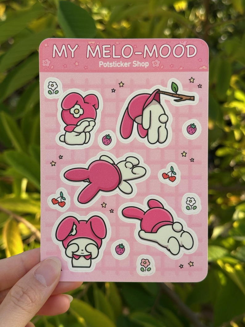 May include: A sheet of pink stickers featuring My Melody, a popular Japanese character. The stickers show My Melody in various poses, including sitting, lying down, and hanging from a branch. The stickers are decorated with stars, flowers, and strawberries.