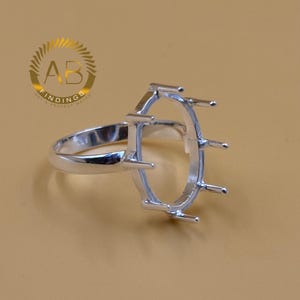 May include: A silver ring setting with an oval bezel and prongs. The ring is on a tan background. The logo "AB FINDINGS GET A PERFECT MATCH" is in the upper left corner.