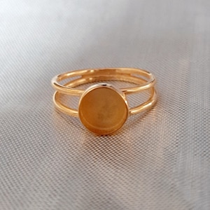 Könnte beinhalten: Ein goldener Ring mit einem Doppelband und einer runden, klaren Steinfassung.