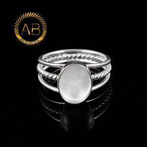May include: Silver ring with three bands, one with a twisted design. The ring has a blank oval bezel for adding a stone or other embellishment.
