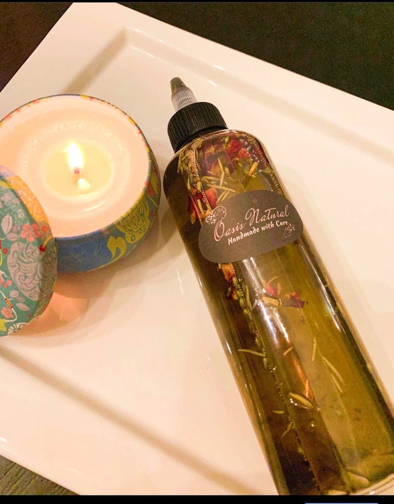 May include: A clear glass bottle with a black cap filled with a green liquid and dried flowers and herbs. The bottle has a white label with the text "Oasis Natural Handmade with Care".