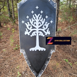 May include: A black shield with a white tree design and star accents. The shield has a silver trim and rivets. The logo "ZIYA COLLECTION" is in the bottom right corner. The shield is displayed outdoors.