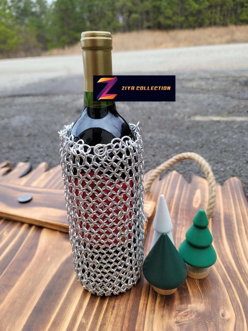 Op de afbeelding: Een fles rode wijn met een zilveren mali&euml;nkolder wijnfleshoes. De fles staat op een houten dienblad met drie decoratieve houten bomen. Het label luidt "ZIYA COLLECTION".