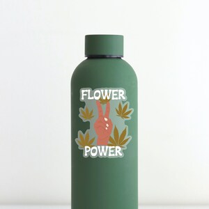 Puede incluir: Una botella de agua reutilizable verde con una pegatina que dice "FLOWER POWER" y presenta un signo de paz y hojas de marihuana.