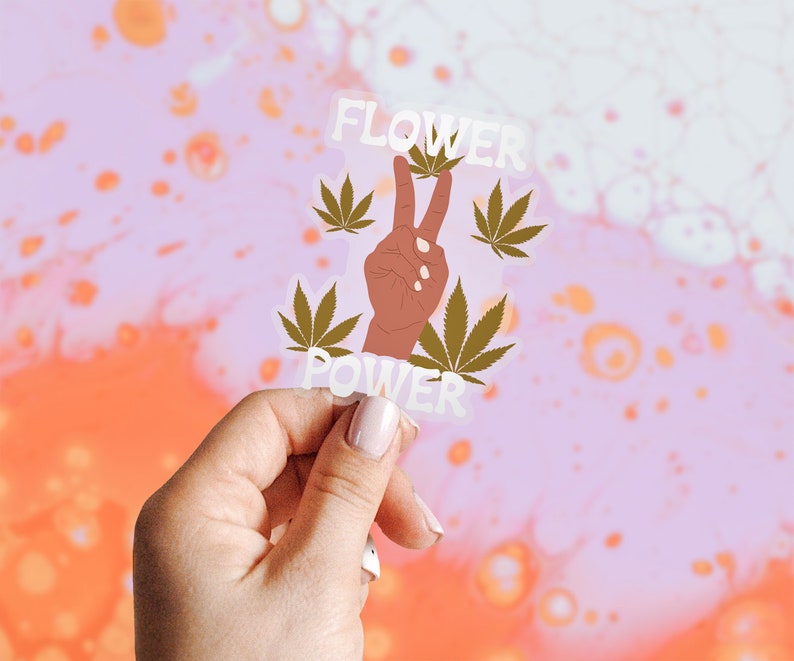 Puede incluir: Una pegatina blanca con un signo de paz, hojas verdes de marihuana y el texto "FLOWER POWER".