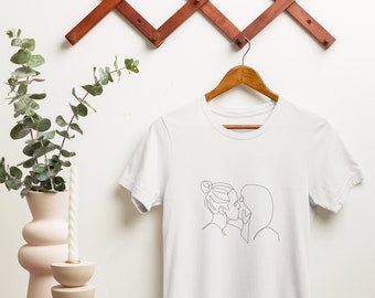 May include: White t-shirt with a line drawing of two people kissing.