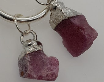 May include: Two silver rings with pink crystal charms attached. The crystals are rough and have a natural, unpolished look.
