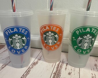 May include: Three clear plastic cups with lids and straws. Each cup has a different colored logo that says "PILATES LOVER" with a green mermaid logo. The logos are blue, orange, and green. The straws have colorful stripes.
