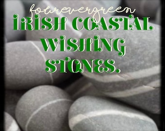 May include: Close-up of smooth, gray stones with white stripes. The stones are arranged in a pile. Text overlay reads "forevergreen irish coastal wishing stones."