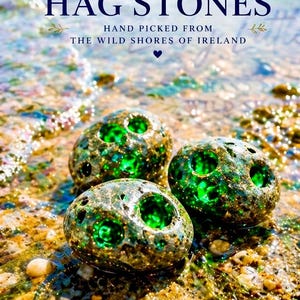 Puede incluir: Tres piedras irlandesas de Hag con centros verdes descansan en una playa arenosa. Las piedras son una mezcla de gris y dorado, con el texto "Irish Hag Stones" y "Hand Picked from the Wild Shores of Ireland" en el fondo.