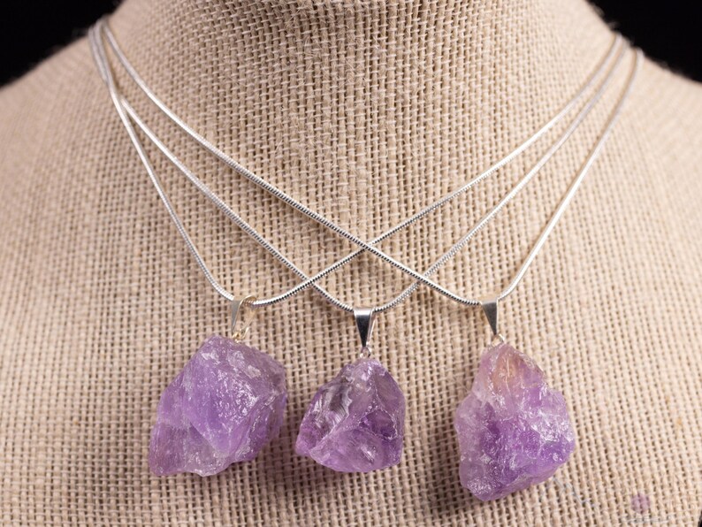 These pale lilac colored Amethyst crystal jewelry sets are raw crystal chunk pendants strung on a silver chain, with matching earrings on silver ear hooks.  
Crystals are nature-made therefore each one is unique in appearance.