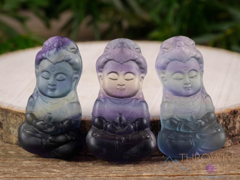 These rainbow Fluorite crystal pendants are carved in the shape of seated Buddha, with a small hole drilled.  Rainbow Fluorite is striated in sheer green, teal, and purple.
Crystals are nature-made therefore each one is unique in appearance.