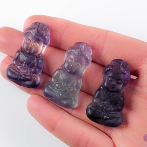 These rainbow Fluorite crystal pendants are carved in the shape of seated Buddha, with a small hole drilled.  Rainbow Fluorite is striated in sheer green, teal, and purple.
Crystals are nature-made therefore each one is unique in appearance.