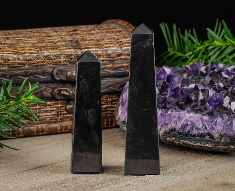 Shungite Crystal Tower. These genuine obelisk shaped crystal carvings are black with a polished finish and are great for crystal grids and decor. Each faceted crystal point is unique and will vary in size, shape, and color. Listing has variations.