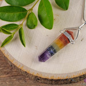 These rainbow chakra crystal pendants are polished double terminated points held in a silver bail.  The points are a composite of different crystals.
Crystals are nature-made therefore each one is unique in appearance.