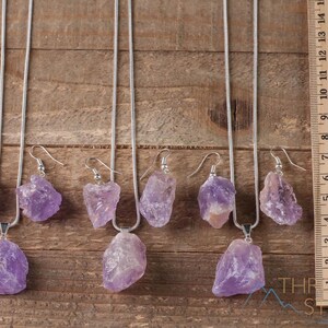 These pale lilac colored Amethyst crystal jewelry sets are raw crystal chunk pendants strung on a silver chain, with matching earrings on silver ear hooks.  
Crystals are nature-made therefore each one is unique in appearance.