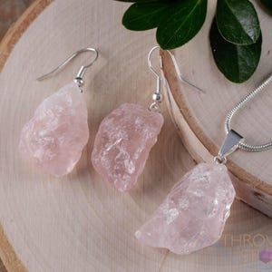 These pale pink Rose Quartz crystal jewelry sets are raw crystal chunk pendants strung on a silver chain, with matching earrings on silver ear hooks.  
Crystals are nature-made therefore each one is unique in appearance.