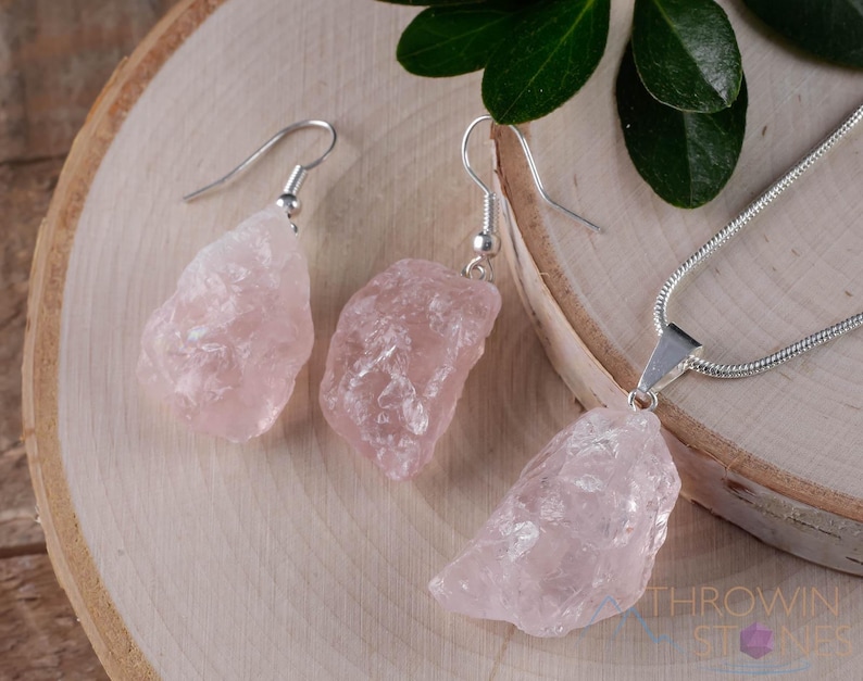 These pale pink Rose Quartz crystal jewelry sets are raw crystal chunk pendants strung on a silver chain, with matching earrings on silver ear hooks.  
Crystals are nature-made therefore each one is unique in appearance.