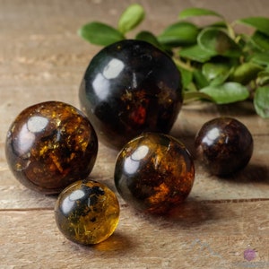 Genuine Amber Crystal Spheres. These semi precious orange crystal balls are between 15 and 40 millimeters in diameter and weigh between 1 and 40 grams. This listing has variations and only medium large and extra large spheres will come with a stand.