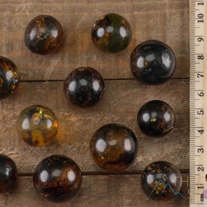 Genuine Amber Crystal Spheres. These semi precious orange crystal balls are between 15 and 40 millimeters in diameter and weigh between 1 and 40 grams. This listing has variations and only medium large and extra large spheres will come with a stand.