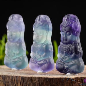 These rainbow Fluorite crystal pendants are carved in the shape of seated Buddha, with a small hole drilled.  Rainbow Fluorite is striated in sheer green, teal, and purple.
Crystals are nature-made therefore each one is unique in appearance.
