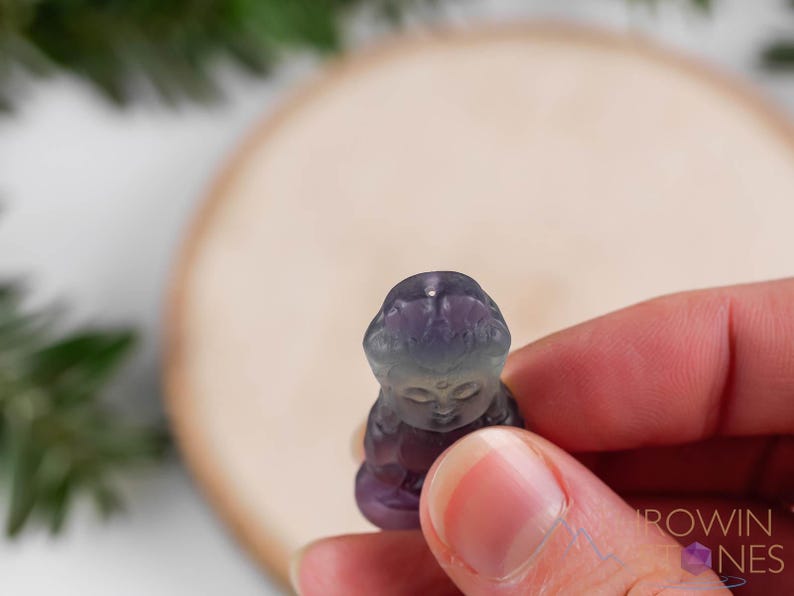 These rainbow Fluorite crystal pendants are carved in the shape of seated Buddha, with a small hole drilled.  Rainbow Fluorite is striated in sheer green, teal, and purple.
Crystals are nature-made therefore each one is unique in appearance.