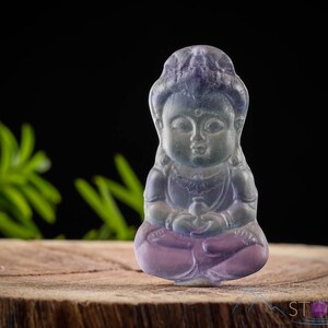 These rainbow Fluorite crystal pendants are carved in the shape of seated Buddha, with a small hole drilled.  Rainbow Fluorite is striated in sheer green, teal, and purple.
Crystals are nature-made therefore each one is unique in appearance.