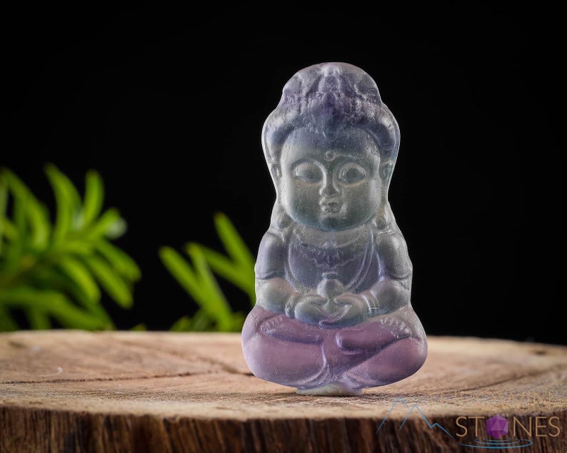 These rainbow Fluorite crystal pendants are carved in the shape of seated Buddha, with a small hole drilled.  Rainbow Fluorite is striated in sheer green, teal, and purple.
Crystals are nature-made therefore each one is unique in appearance.