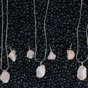 These pale pink Rose Quartz crystal jewelry sets are raw crystal chunk pendants strung on a silver chain, with matching earrings on silver ear hooks.  
Crystals are nature-made therefore each one is unique in appearance.
