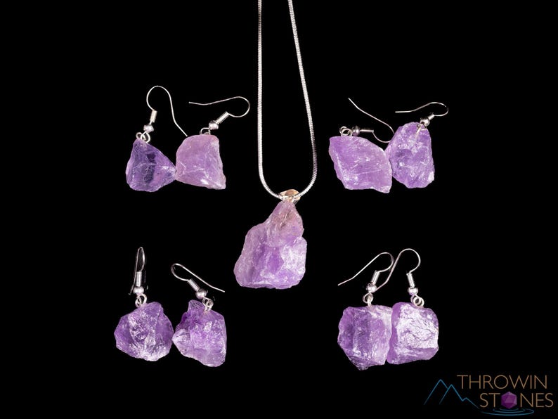 These pale lilac colored Amethyst crystal jewelry sets are raw crystal chunk pendants strung on a silver chain, with matching earrings on silver ear hooks.  
Crystals are nature-made therefore each one is unique in appearance.