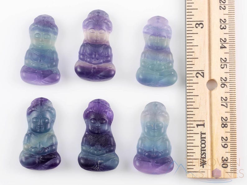 These rainbow Fluorite crystal pendants are carved in the shape of seated Buddha, with a small hole drilled.  Rainbow Fluorite is striated in sheer green, teal, and purple.
Crystals are nature-made therefore each one is unique in appearance.
