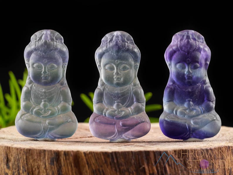 These rainbow Fluorite crystal pendants are carved in the shape of seated Buddha, with a small hole drilled.  Rainbow Fluorite is striated in sheer green, teal, and purple.
Crystals are nature-made therefore each one is unique in appearance.