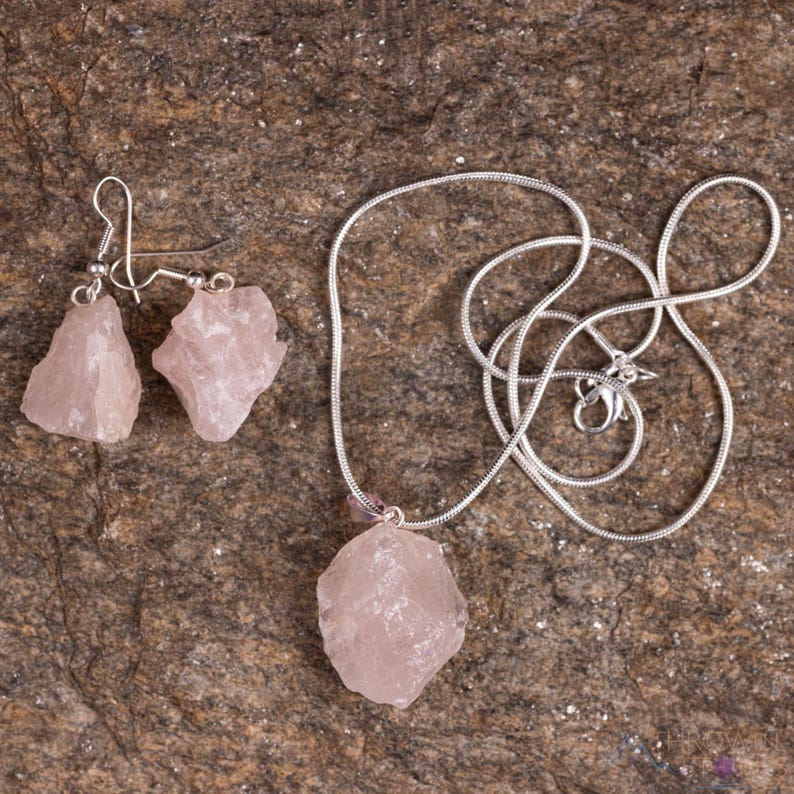 These pale pink Rose Quartz crystal jewelry sets are raw crystal chunk pendants strung on a silver chain, with matching earrings on silver ear hooks.  
Crystals are nature-made therefore each one is unique in appearance.
