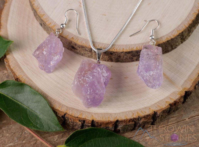 These pale lilac colored Amethyst crystal jewelry sets are raw crystal chunk pendants strung on a silver chain, with matching earrings on silver ear hooks.  
Crystals are nature-made therefore each one is unique in appearance.