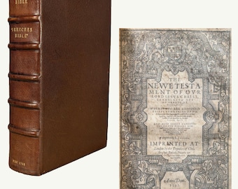 May include: A brown leather-bound book with raised bands on the spine, labeled BIBLE and BREECHES BIBLE, alongside an open page titled THE NEW TESTAMENT OF OVR LORD IESVS CHRIST, IMPRINTED AT LONDON BY THE DEPVTIES OF CHRISTOPHER BARKER, ANNO DOM 1591.