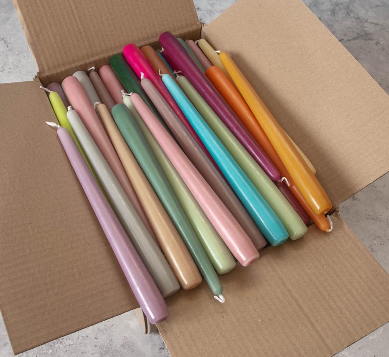 May include: A box filled with a variety of taper candles in assorted colors, including pink, green, yellow, orange, and blue.