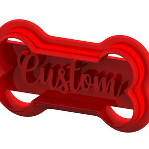 May include: Red plastic cookie cutter shaped like a bone with the word "Custom" cut out in the center.