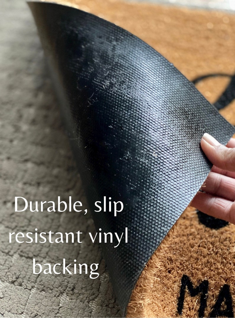 May include: Close-up of the back of a coir doormat with a black, textured, slip-resistant vinyl backing. The text "Durable, slip resistant vinyl backing" is visible in white text.