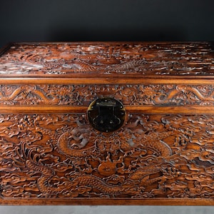 May include: A wooden chest with intricate carvings of dragons and clouds. The chest has a brass latch and hinges.
