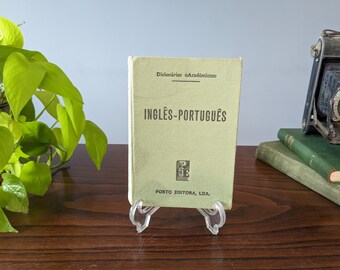 Könnte beinhalten: Ein grünes Hardcover-Buch mit dem Titel "Dicionários Acadêmicos Englisch-Portugiesisch" von Porto Editora, LDA.