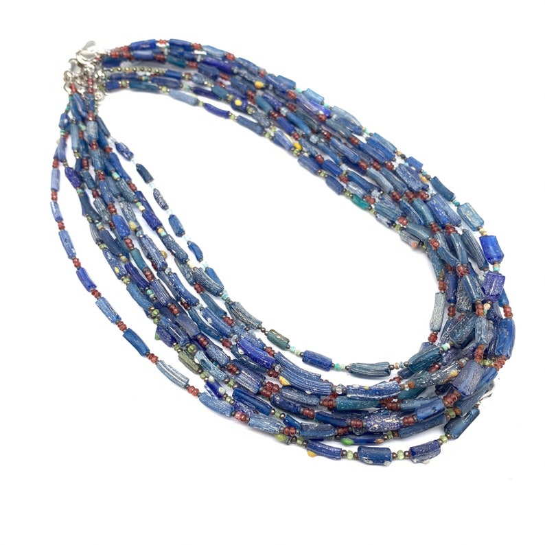 Peut inclure: Un collier multi-rangs compos&eacute; de perles de verre bleues, rouges et vertes. Les perles sont de formes et de tailles diff&eacute;rentes et sont enfil&eacute;es sur une cha&icirc;ne en argent.