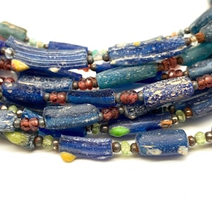 Peut inclure: Un collier de perles en verre bleu, vert et rouge. Les perles sont de forme irr&eacute;guli&egrave;re et ont une surface textur&eacute;e.